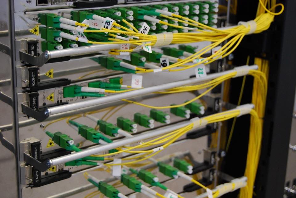 Yellow fibre optic cables with green connectors going into network switches in a server rack